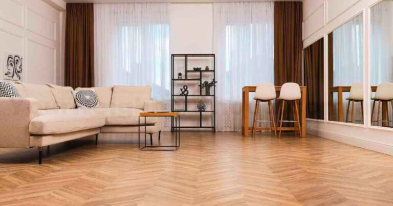 Modern living room with herringbone SPC flooring in Kerala, featuring a light beige sofa, brown curtains, and a minimalist black shelf.