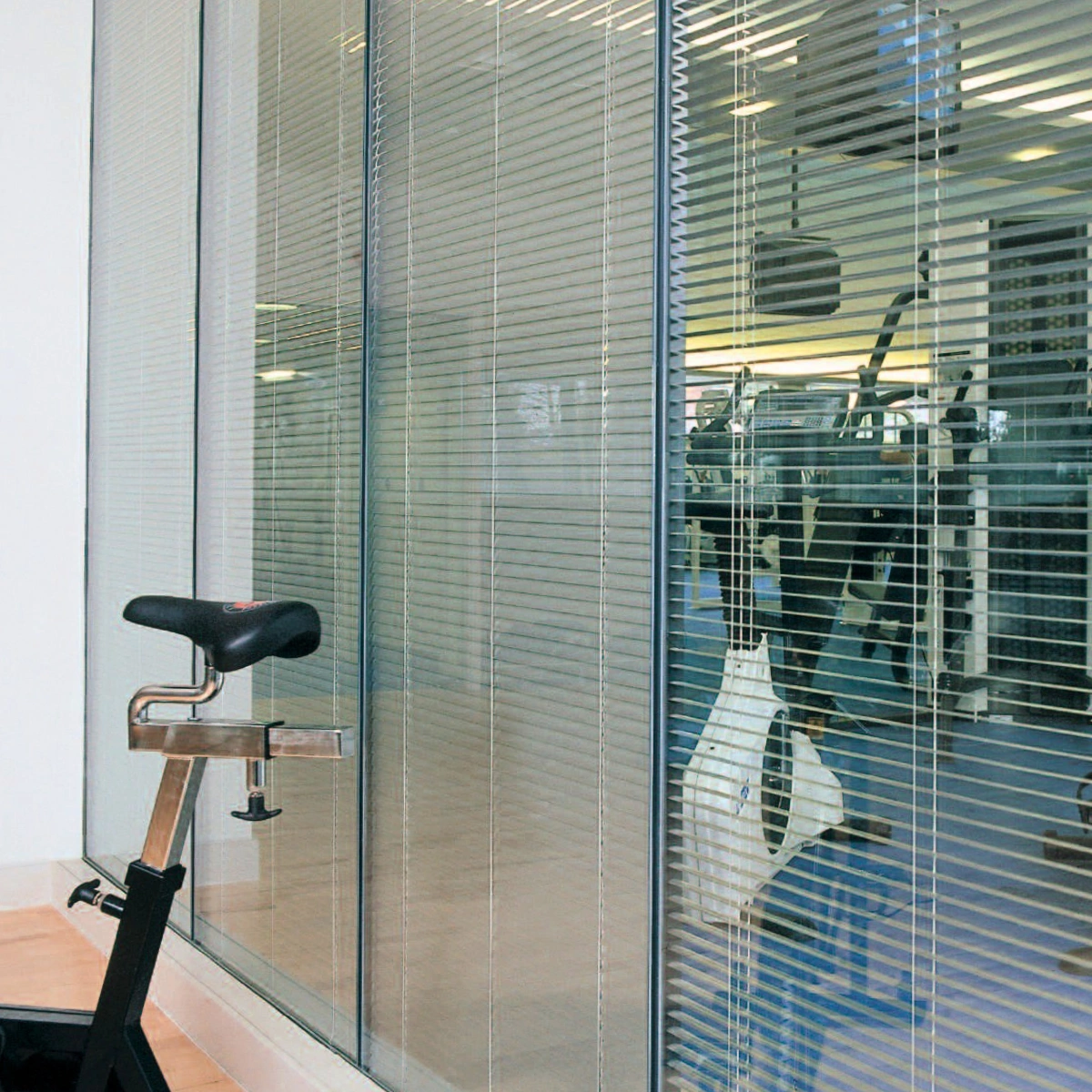 A gym with Hunter Douglas Venetian blinds installed on glass partition